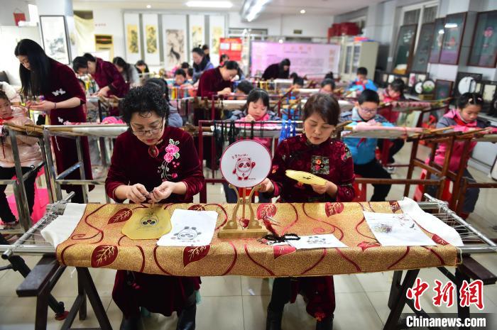 江西省級非遺豫章繡傳承人手把手指導(dǎo)小學(xué)生繡制2022年北京冬奧會吉祥物“冰墩墩”形象。　喻云亮 攝
