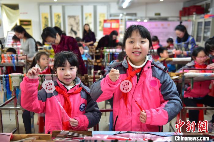 圖為小學(xué)生展示繡制好的2022年北京冬奧會吉祥物“冰墩墩”形象?！∮髟屏?攝