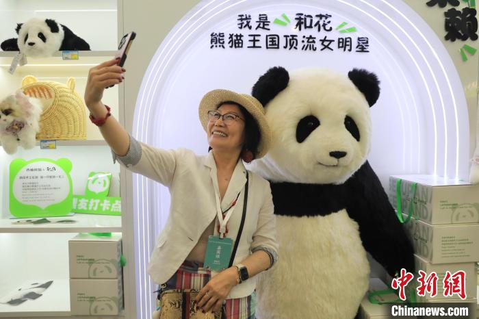 美國華視總裁楊蓮花與大熊貓文創(chuàng)產品合影。　王磊 攝