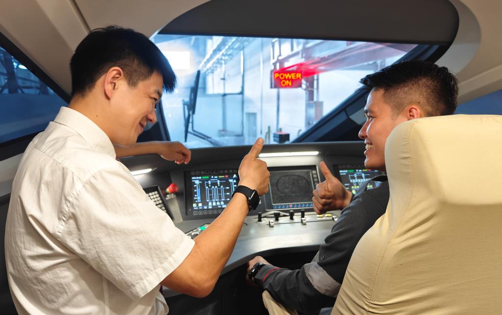 8月25日，在印度尼西亞萬隆的雅萬高鐵德卡魯爾動車所內，中國師傅穆振（左）在向印尼火車司機塞蒂亞萬講解動車組出庫前的上電作業。
