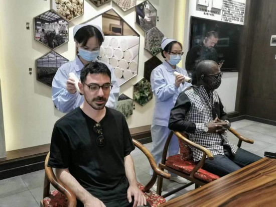 2023“一帶一路”媒體合作論壇聯合采訪團團員在九牛草展示館體驗艾灸。（本報記者 黃超攝）