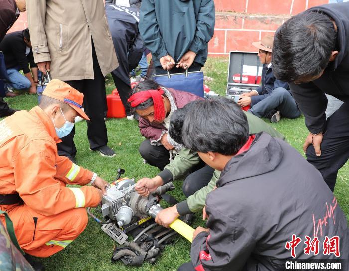 圖為森林消防員為護(hù)林員講解滅火裝備的使用方法?！〔际猩窒乐ш?duì) 供圖
