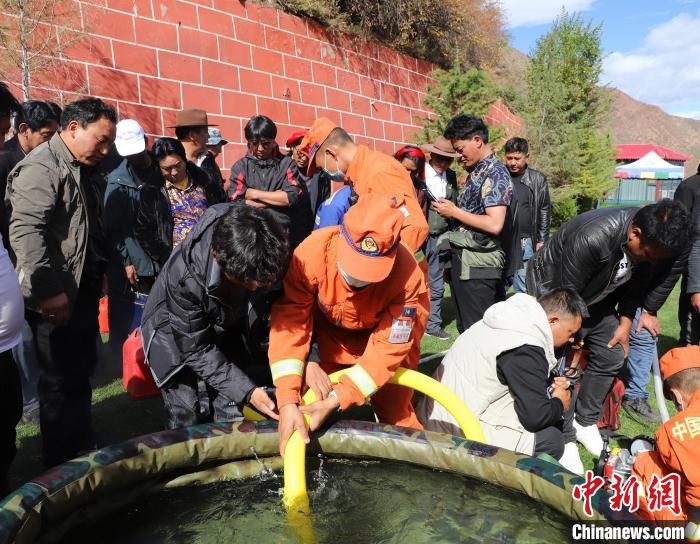 圖為森林消防員為護(hù)林員講解滅火裝備的使用方法?！〔际猩窒乐ш?duì) 供圖