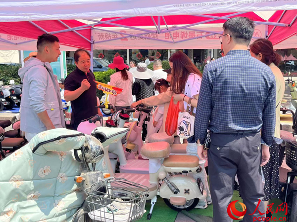某電動自行車品牌工作人員向消費(fèi)者介紹以舊換新相關(guān)情況。人民網(wǎng)記者 杜燕飛攝
