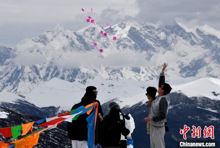 圖為5月14日，游客在西藏林芝色季拉山觀景臺拋灑“隆達”(風馬旗，藏族民眾的一種祈福方式)?！±盍?攝