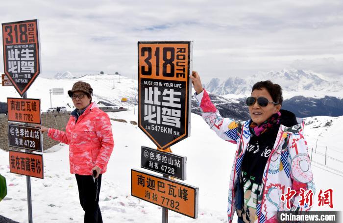 圖為5月14日，西藏林芝色季拉山觀景臺，游客與南迦巴瓦峰合影。　李林 攝